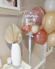 Colorful balloons floating in a room with a vase on a table.