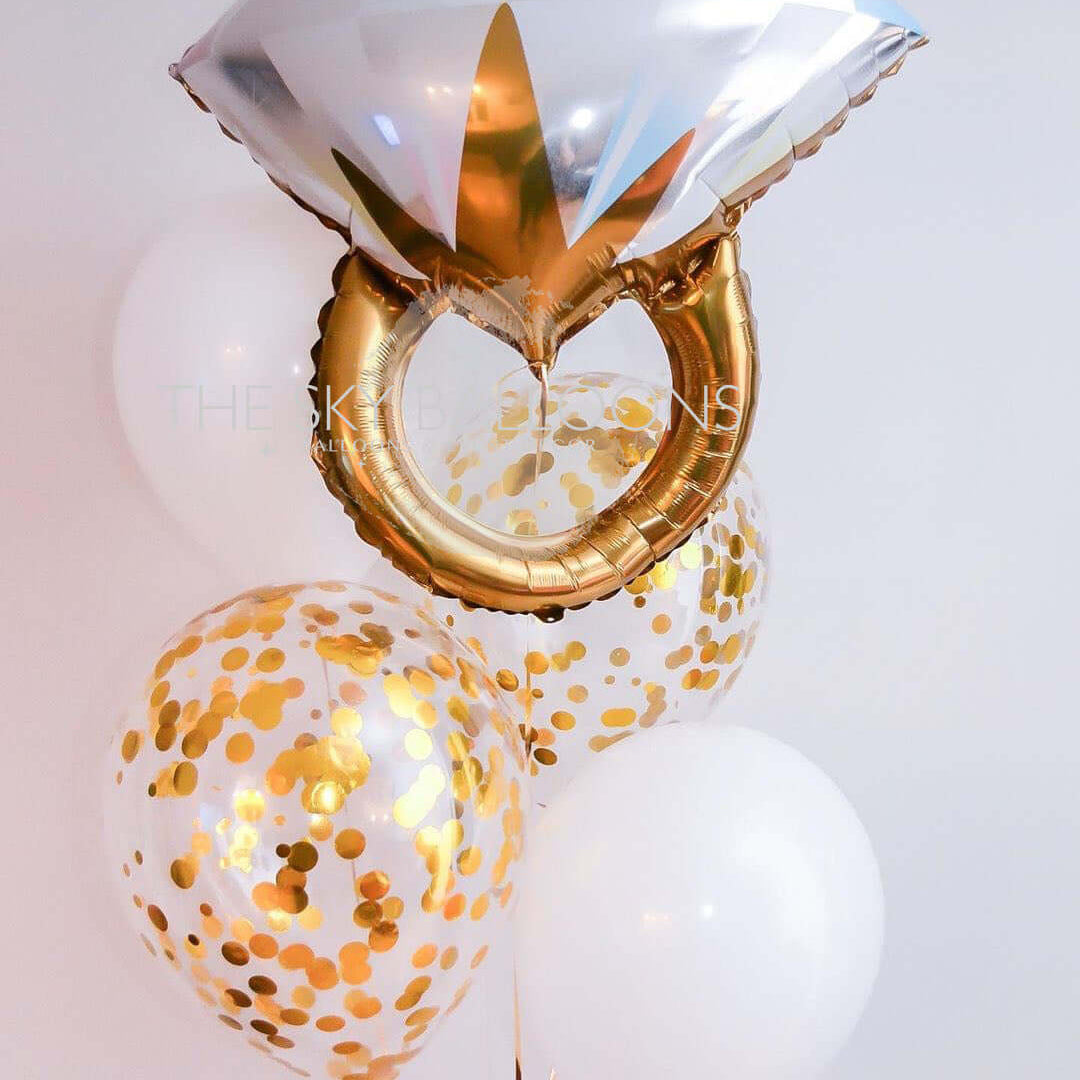A set of balloons including a latex balloon, a confetti balloon, and a diamond ring balloon, all with a gold and white color scheme and filled with helium gas.