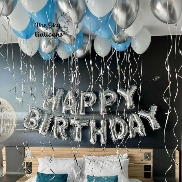 A 'Happy Birthday' balloon arrangement featuring silver and blue balloons along with a banner.