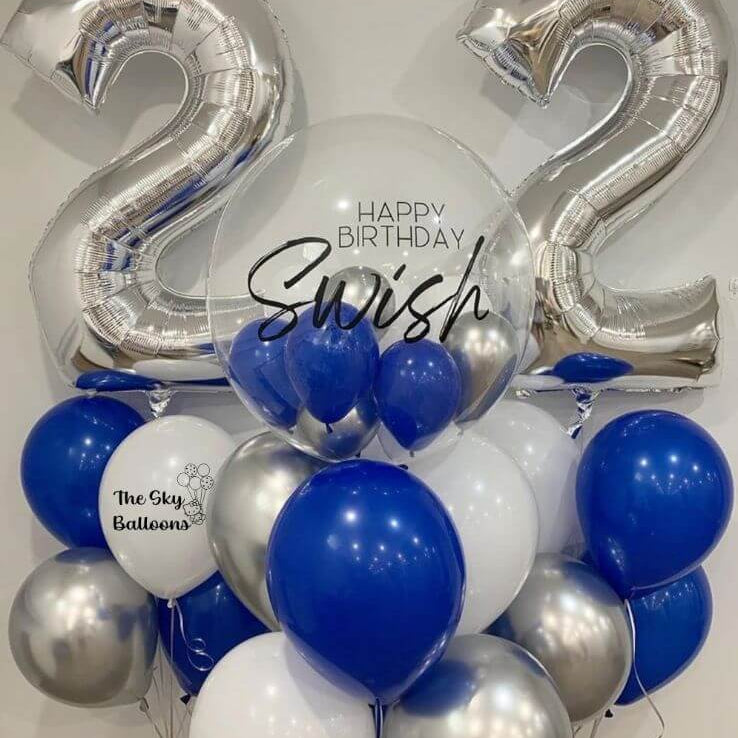 A balloon bouquet featuring silver and blue helium-filled balloons, including large foil numbers '22', a customized balloon with the name 'Swish', and a balloon weight.