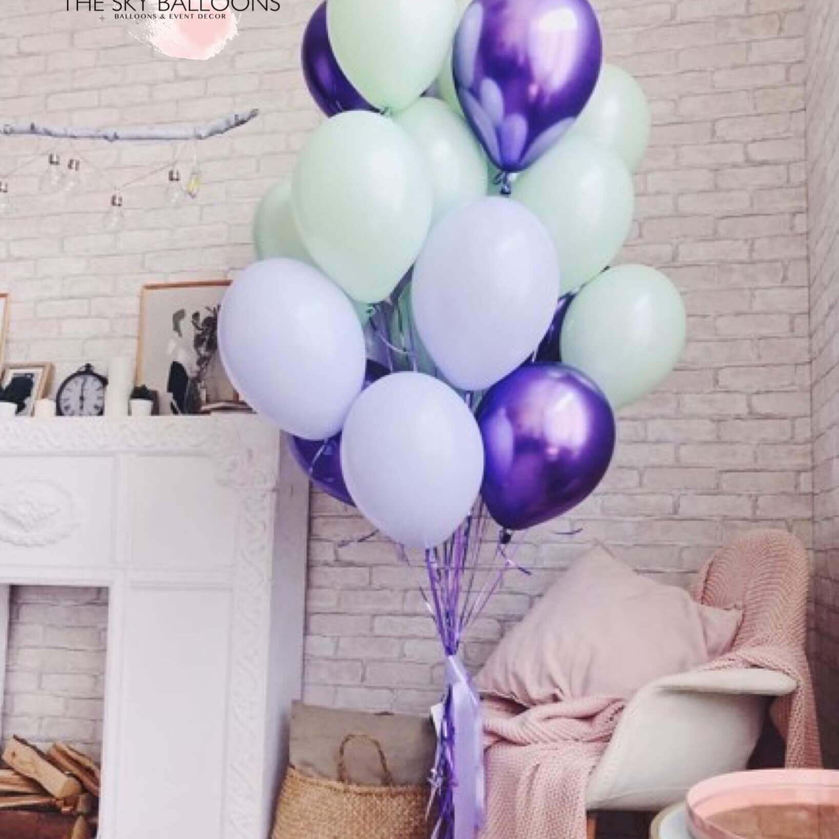 A bouquet of inflated balloons in various shades of purple, green, and white, tied together with a purple ribbon.