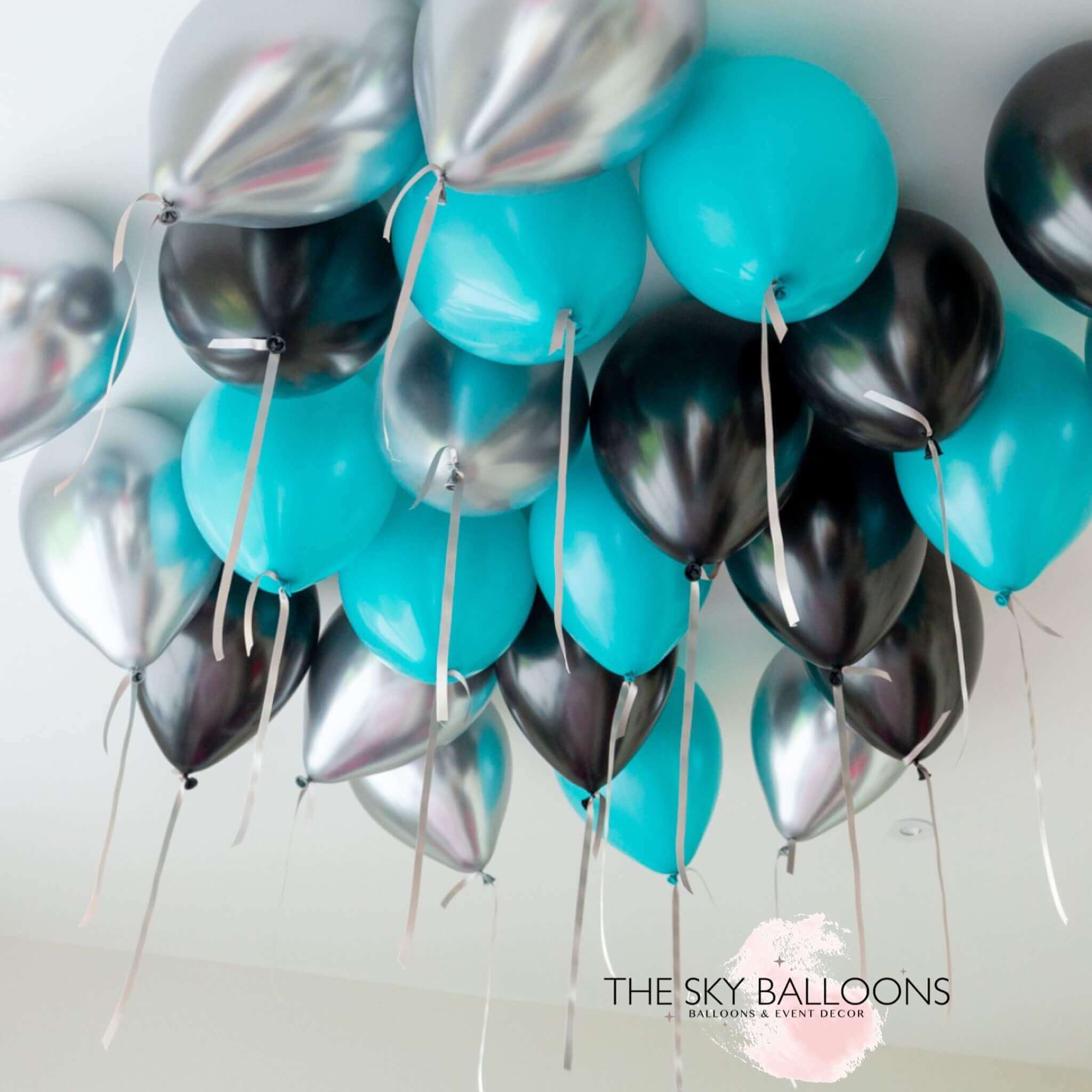 A cluster of inflated ceiling balloons in aquamarine, chrome (silver), and other colors, arranged to float in the air.