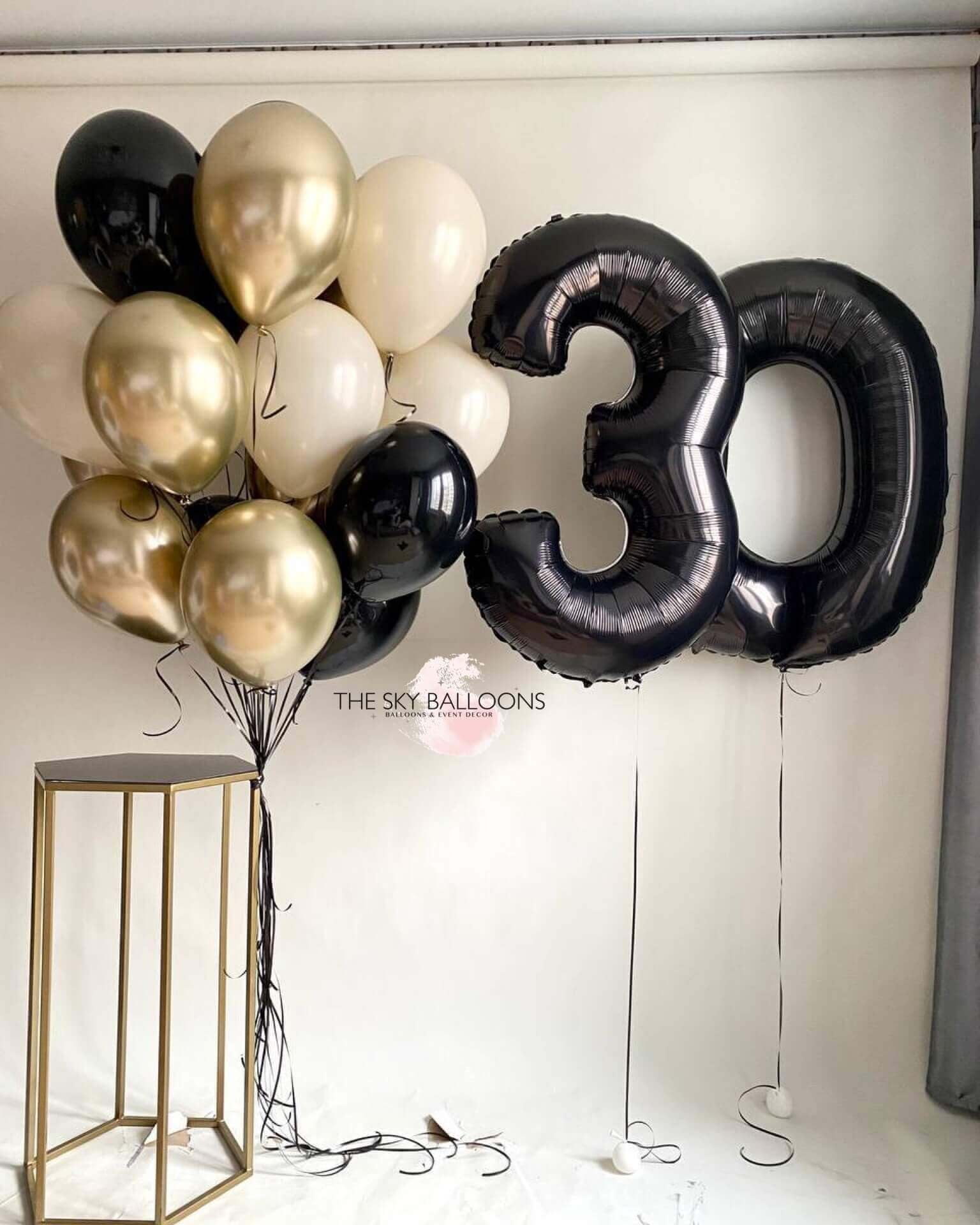 A bouquet of balloons featuring gold, black, and white colors, with large black numerical foil balloons '30' included.