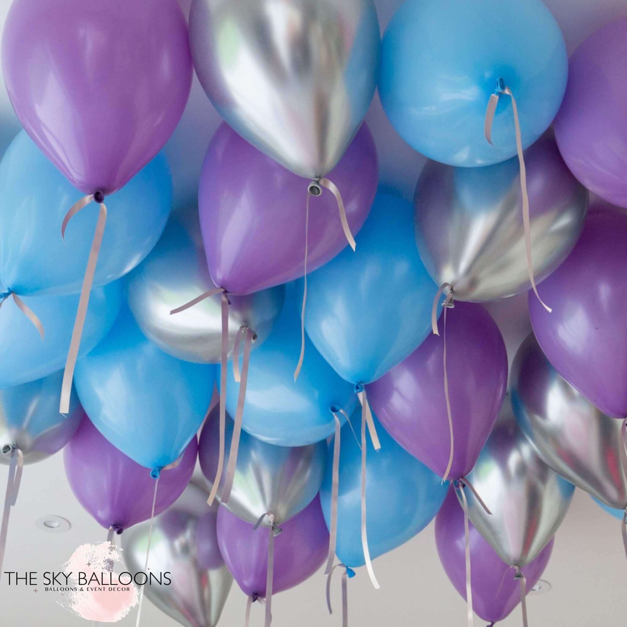 A cluster of helium-filled balloons in shades of purple, blue, and silver, attached to strings, meant for ceiling decoration.