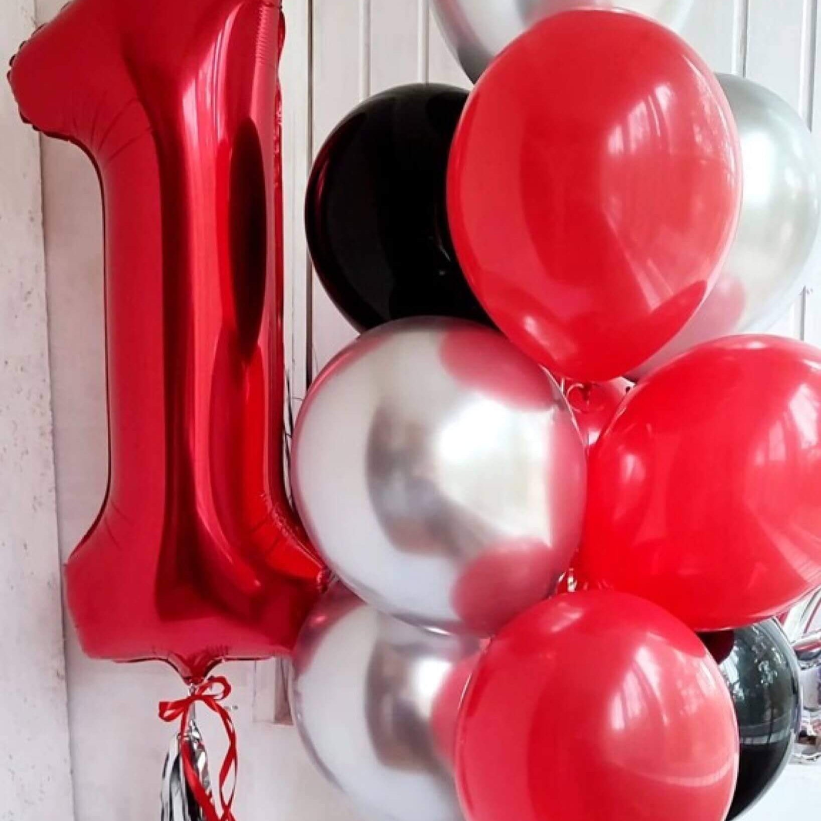 A bouquet of round latex balloons in red, silver, and black colors, with a large foil balloon in the shape of the number 1.