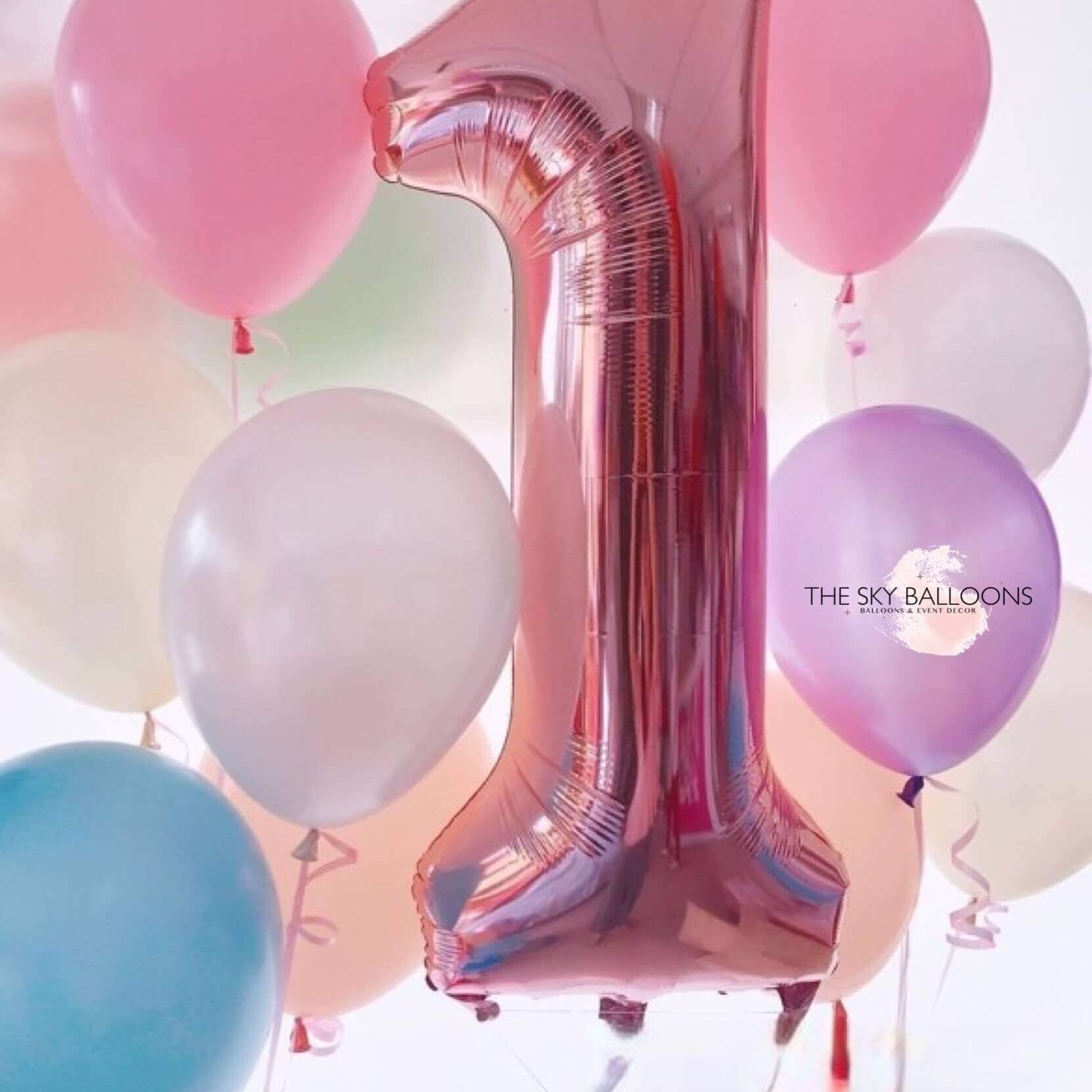 A helium-filled balloon designed to form the number '1', surrounded by various colored balloons with 'The Sky Balloons' written on the side.
