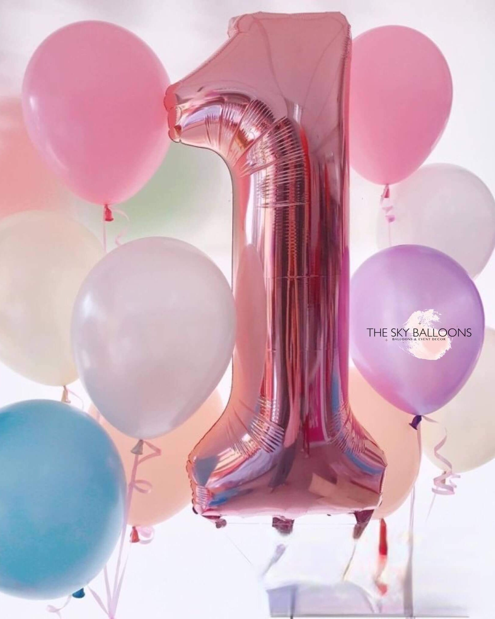 A helium-filled balloon designed to form the number '1', surrounded by various colored balloons with 'The Sky Balloons' written on the side.