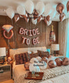 A bedroom adorned with balloons and a bed featuring a "Bride to Be" sign.