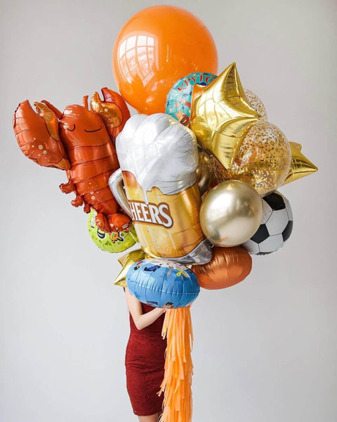 A vibrant collection of character foil balloons, including a lobster, soccer ball, and cheers beer design.