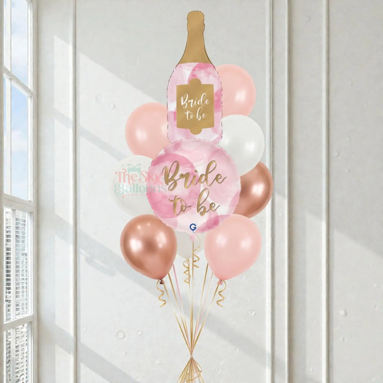 Decorative balloon bouquet with 'Bride to be' and champagne bottle design in a bright room.