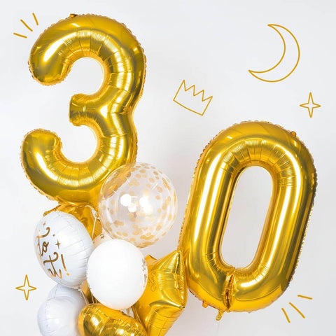Woman sitting on the floor with large iridescent number balloons spelling '89' on a white background