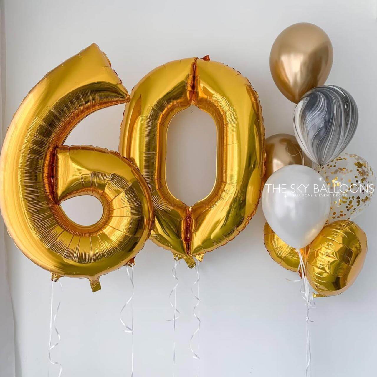 Gold '60' balloons with other balloons against a white background