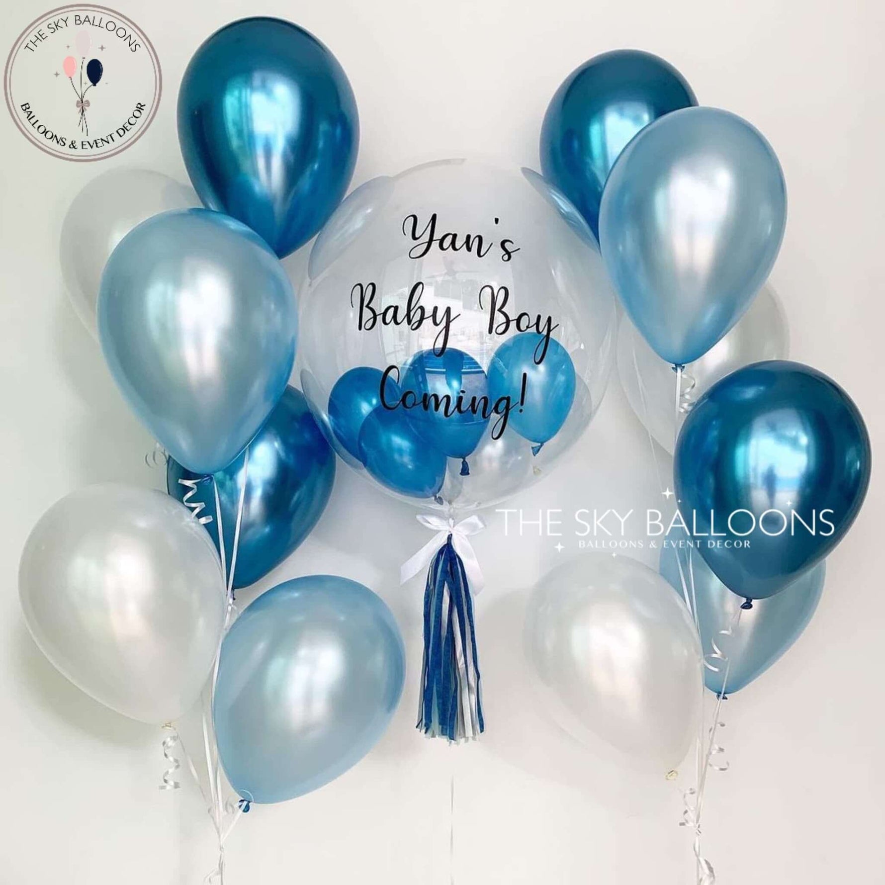 A bouquet of blue balloons with the text 'Yan's Baby Boy Coming!' printed on a helium-filled balloon, with additional latex balloons attached.