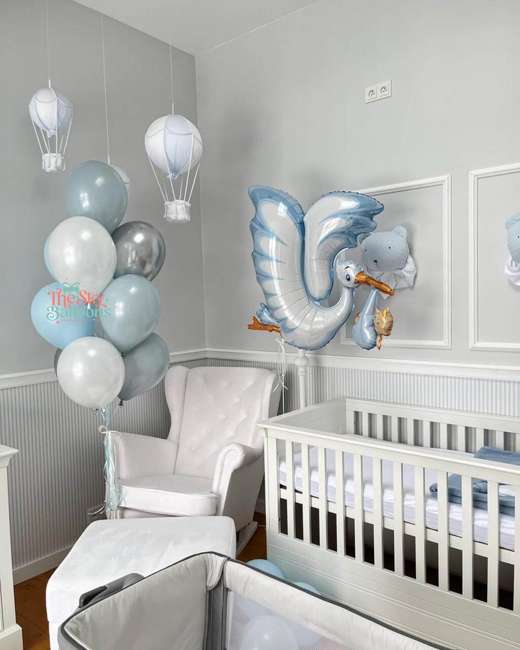 Nursery room with baby crib, balloons, and stork balloon decoration.