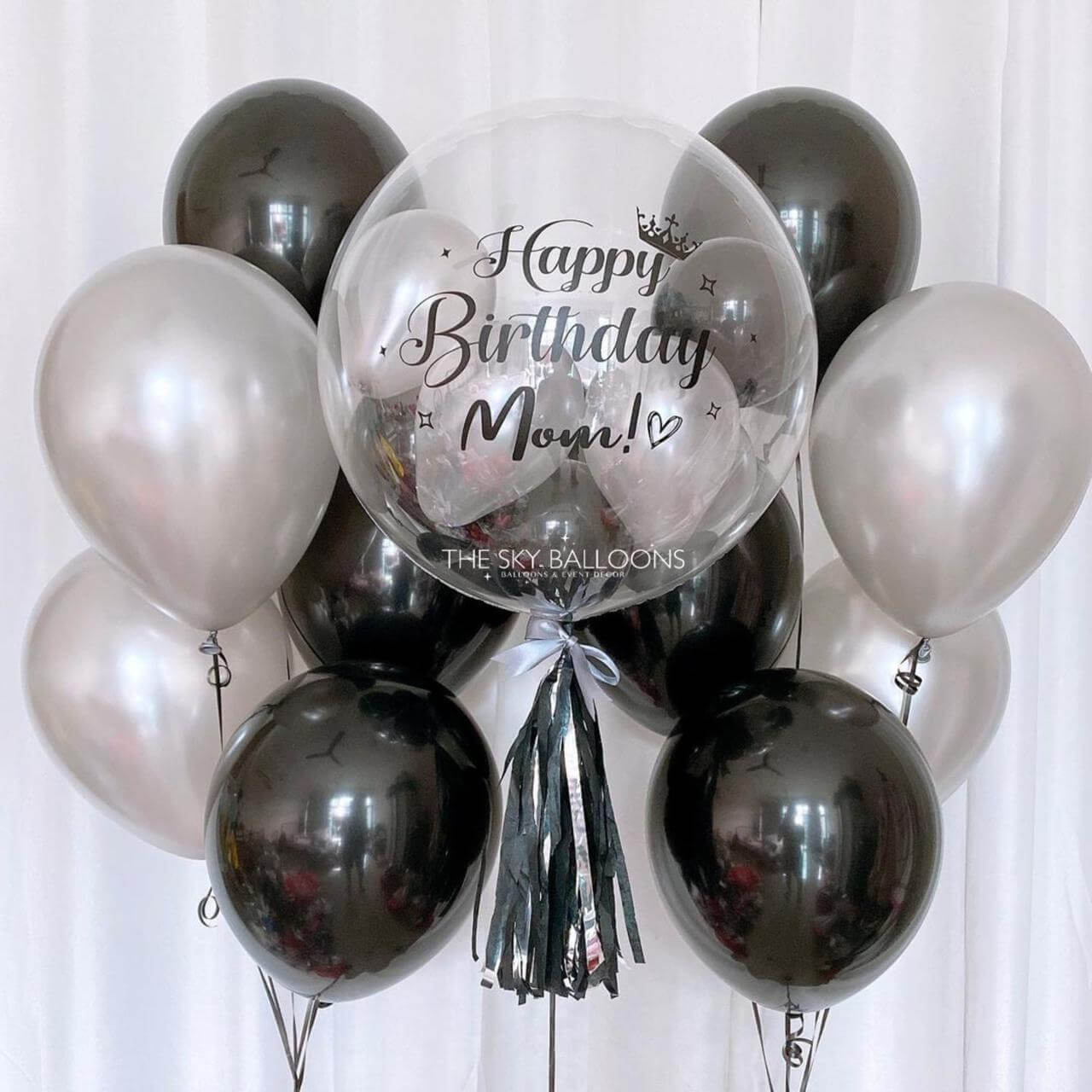 Balloon bouquet with 'Happy Birthday Mom!' message against a white background