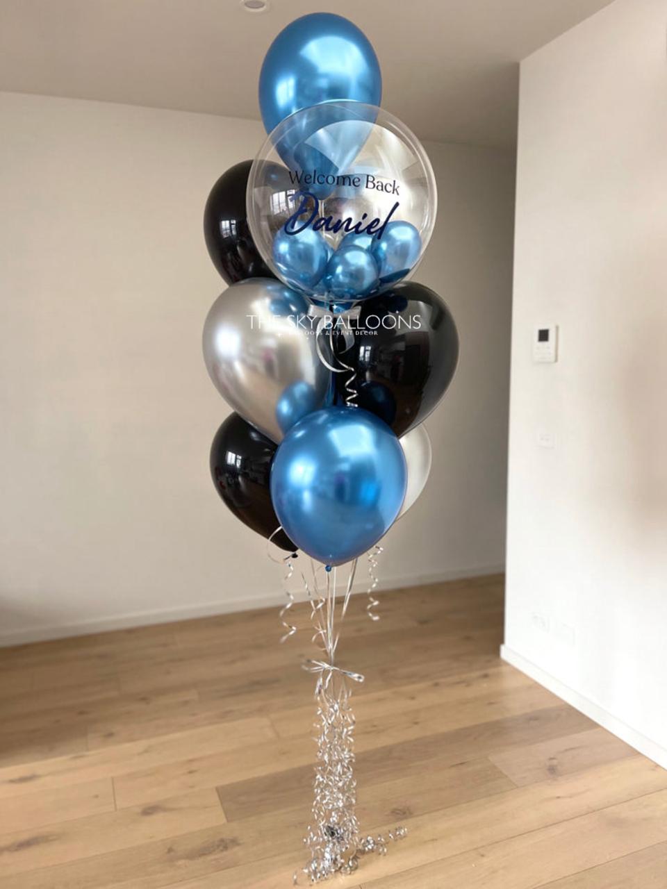 Balloon bouquet with blue, silver, and black balloons in a room.
