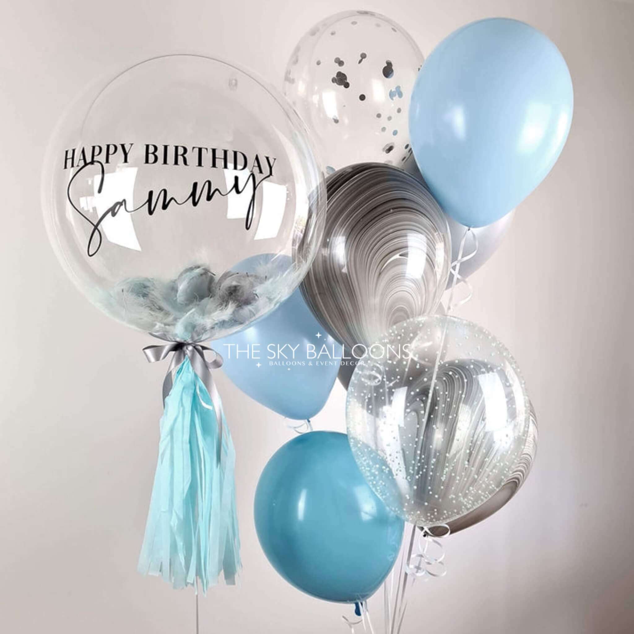 Balloon bouquet with 'Happy Birthday Sammy' on a clear balloon against a light background.