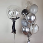 A shiny silver and black balloon with "Happy Birthday" printed on it, adding celebration vibes.
