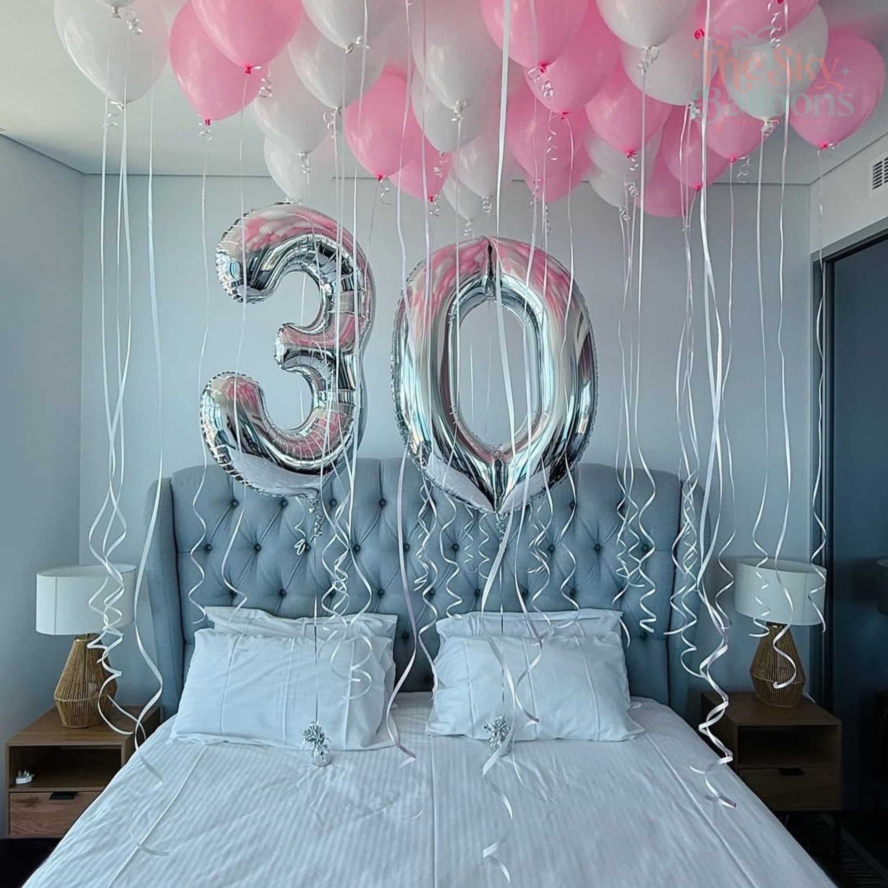 Bedroom with balloons and '30' balloons above a bed