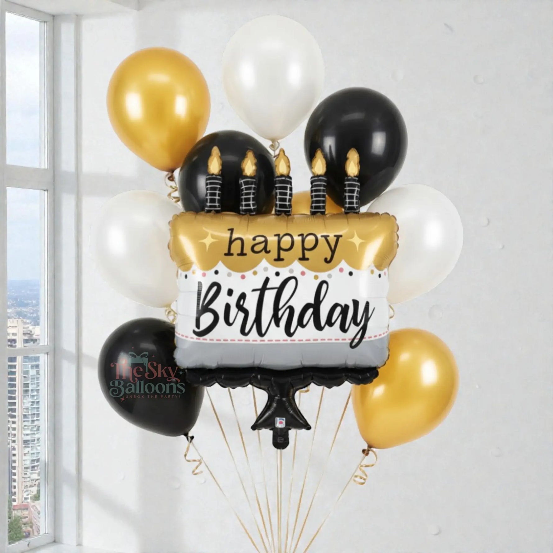 Birthday balloon bouquet with black, gold, and white balloons and a 'happy birthday' sign.