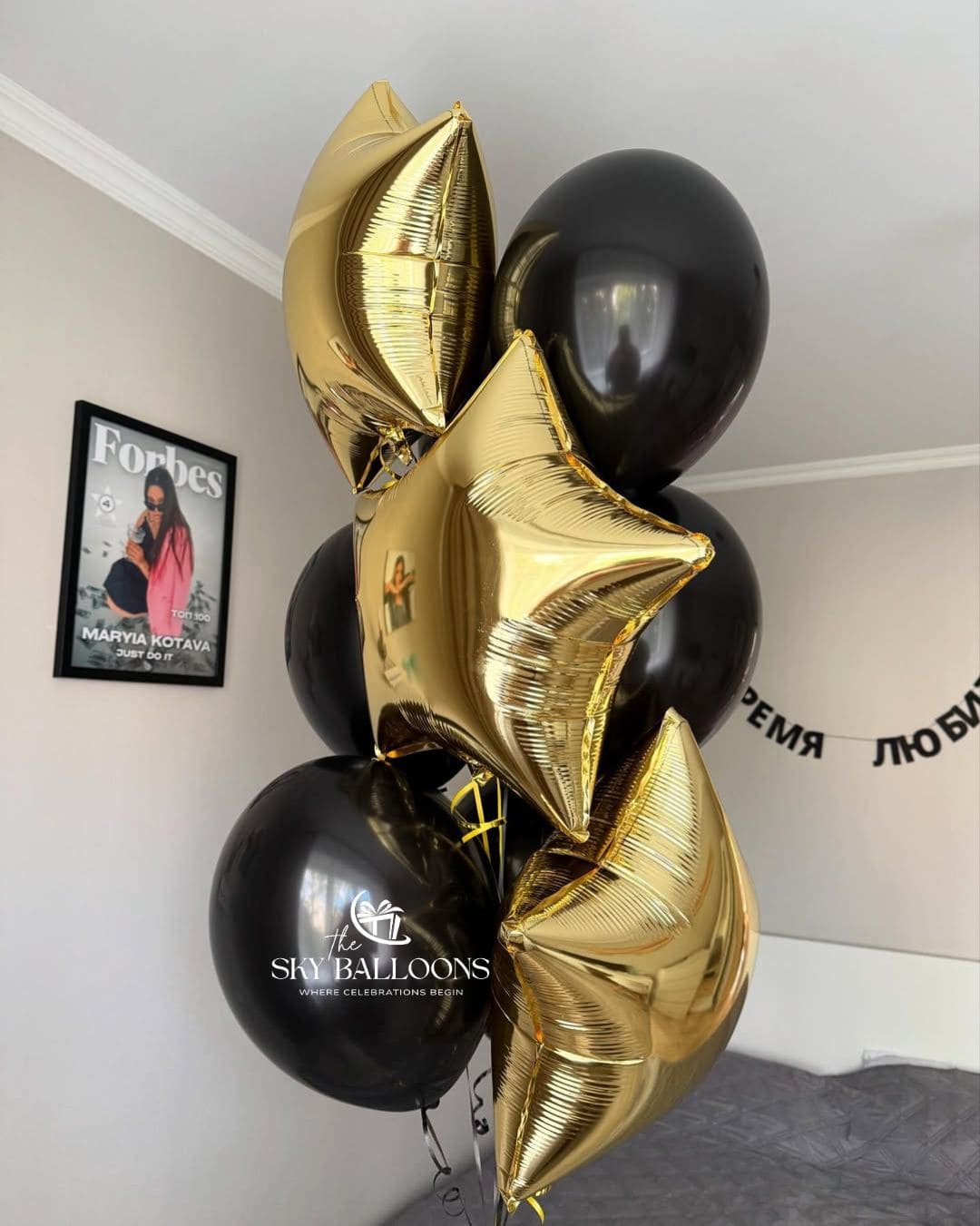 Black and gold balloon bouquet with gold star-shaped foil balloons and glossy black latex balloons tied together with curling ribbons.