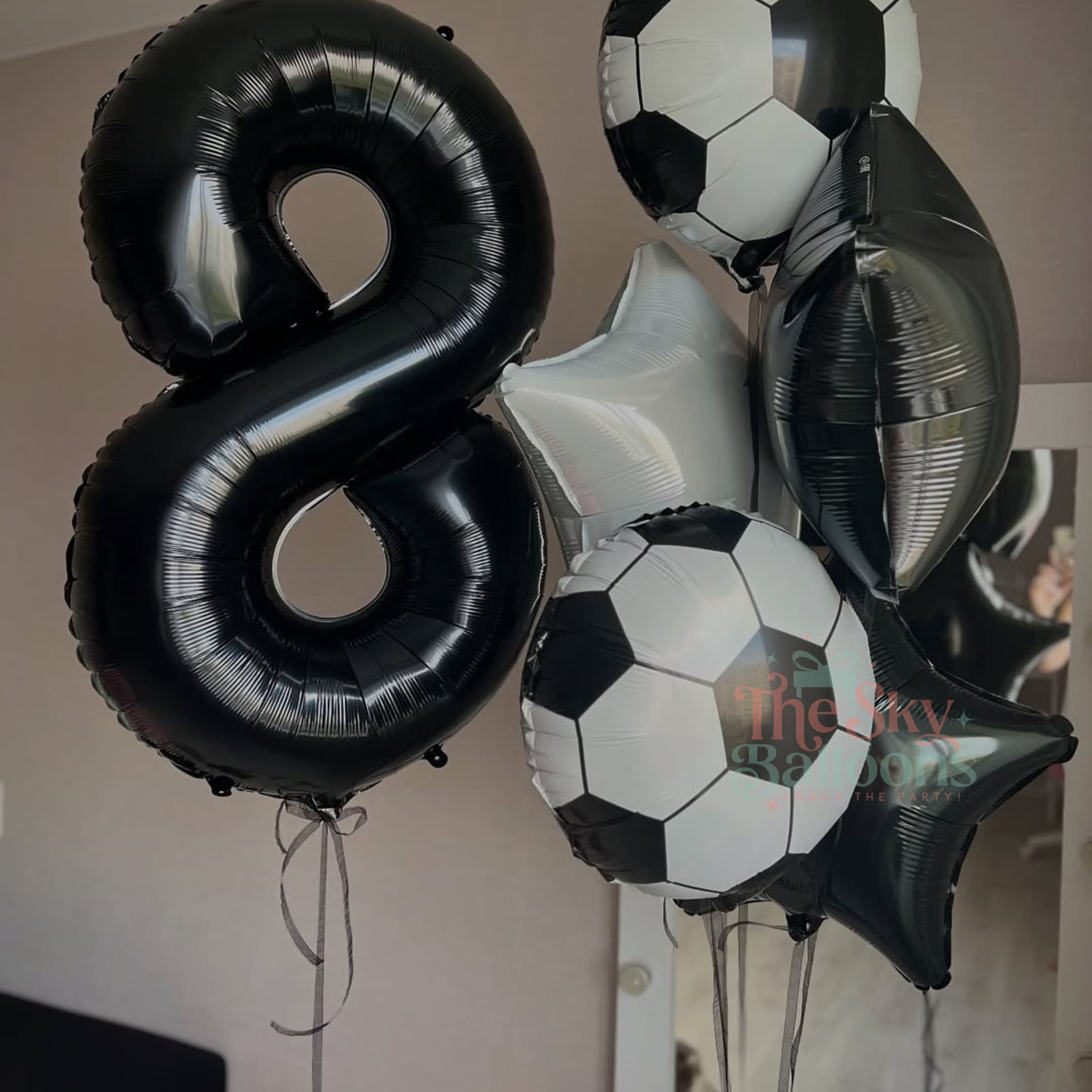 Black and white balloons including a large number '8' and soccer ball designs.