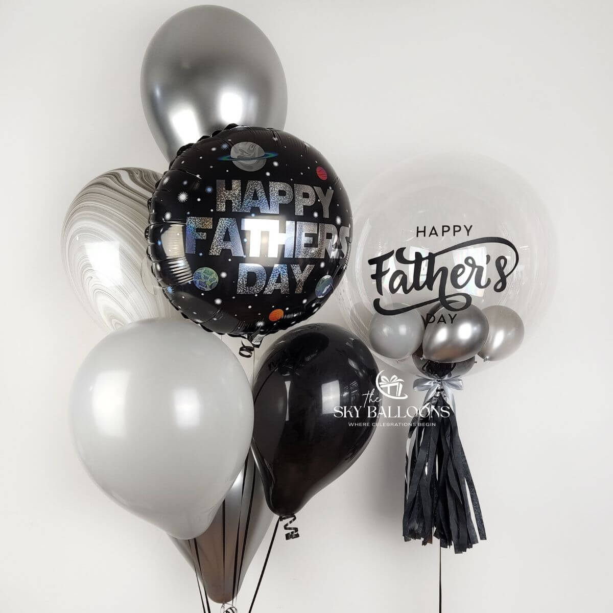 Black, silver and marble-effect latex balloons with a Happy Father’s Day foil and customised clear bubble balloon with black tassels.