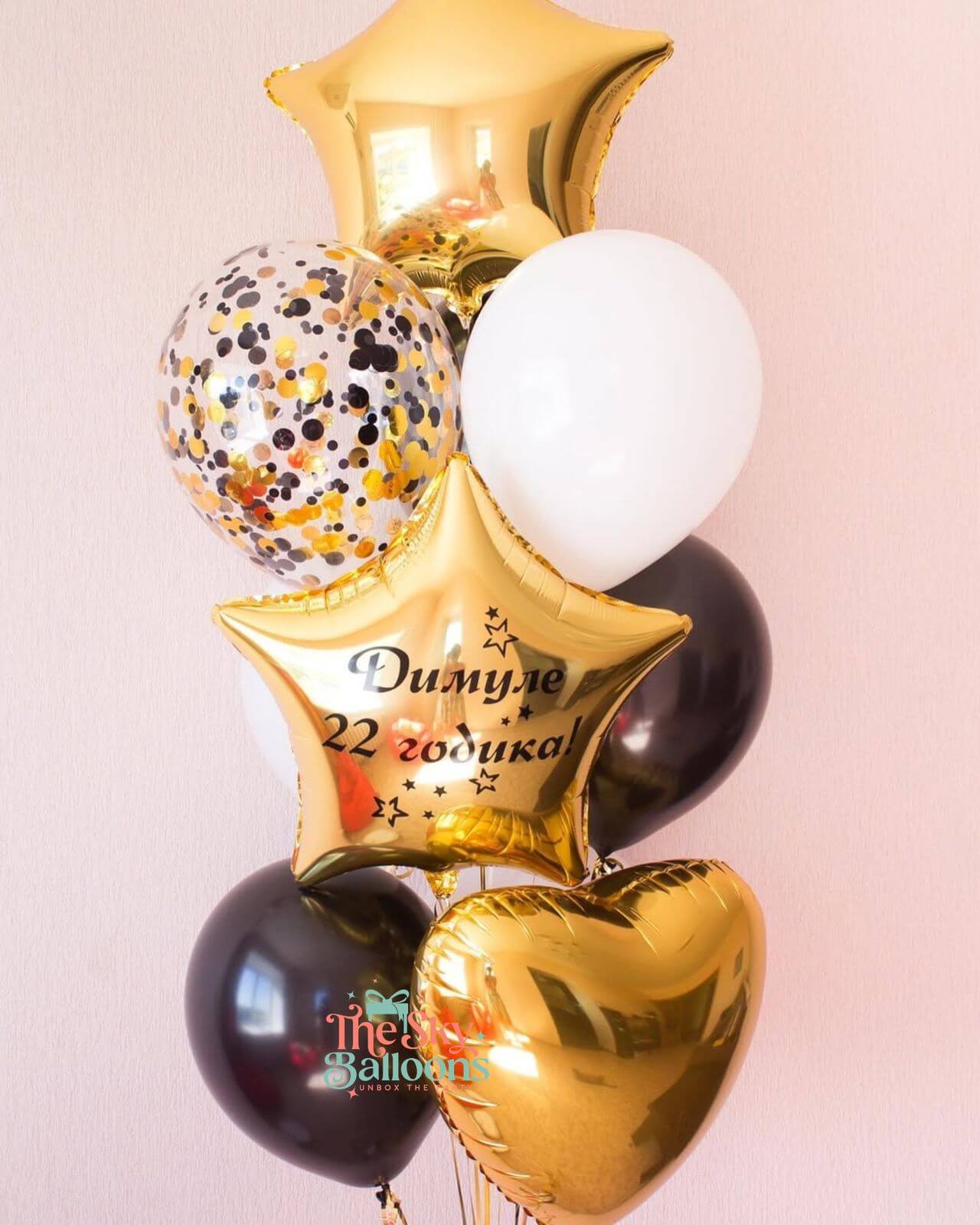 Decorative balloons with gold stars, black and white balloons on a light pink background