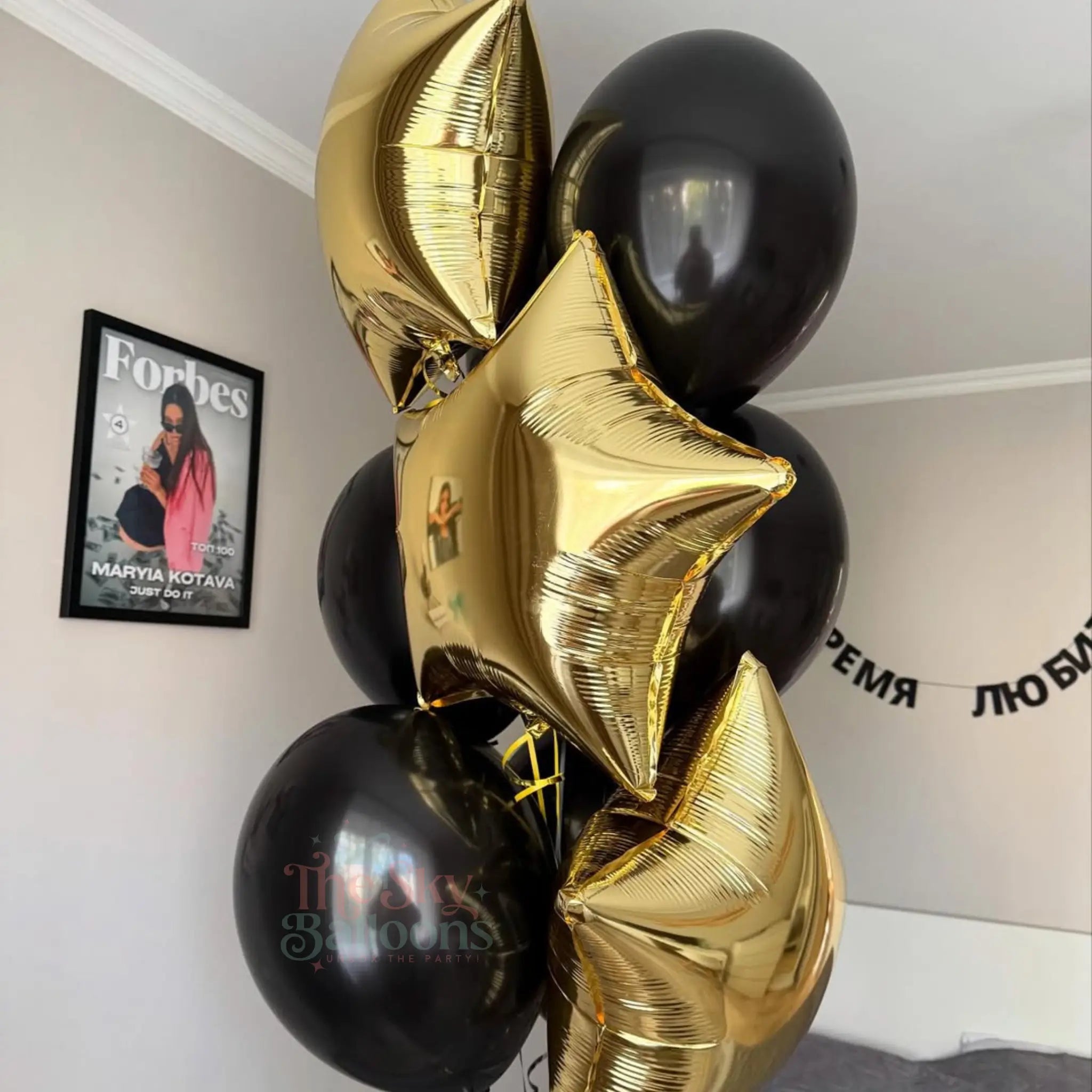 Black and gold balloons with a Forbes magazine in the background