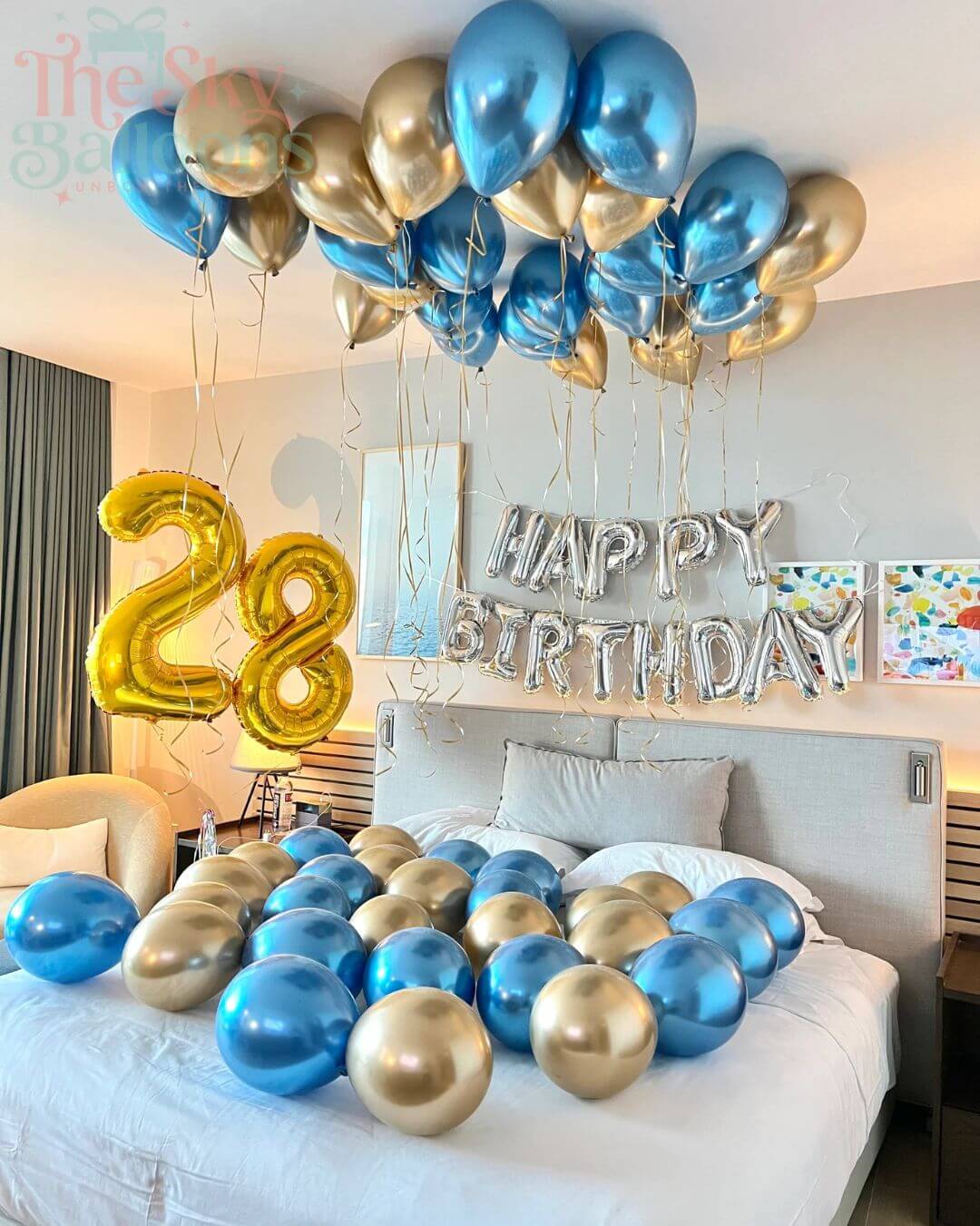 Birthday decorations with balloons and 'Happy Birthday' sign on a bed.