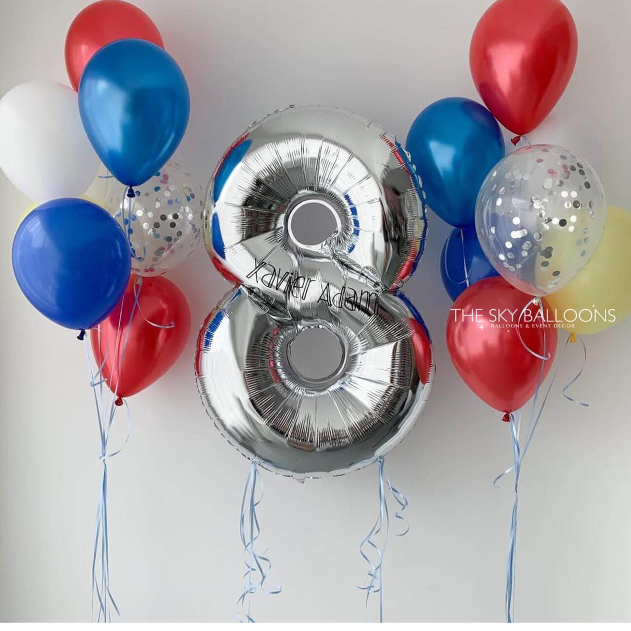 Silver number 8 balloon with red, blue, and white balloons on a light background
