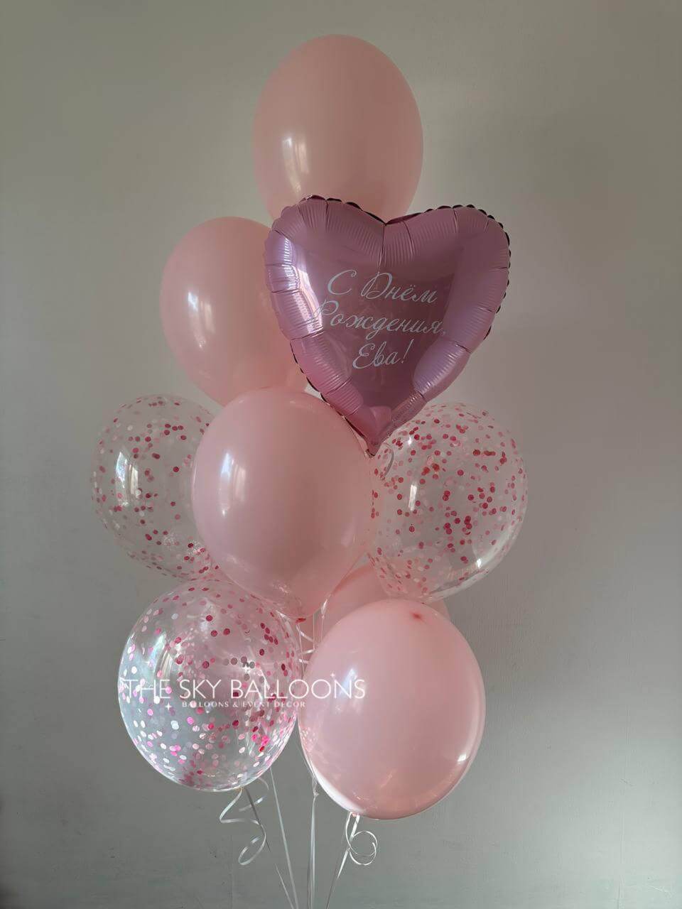Bouquet of pink balloons with a heart-shaped balloon featuring text, against a plain background.