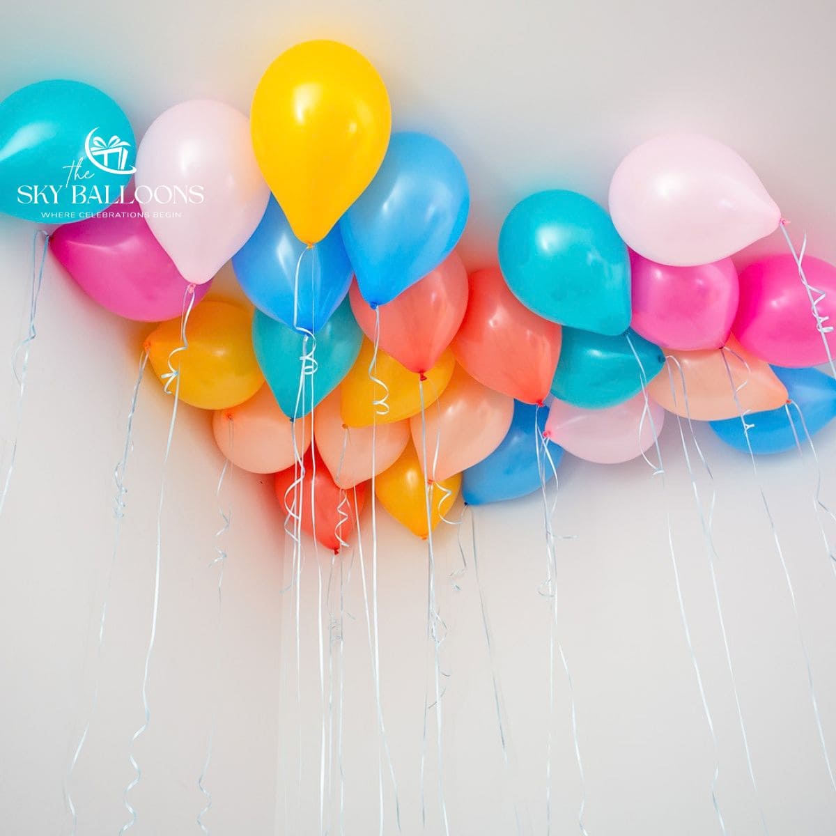Blue, turquoise, yellow, coral, peach and pink helium ceiling balloons with hanging curling ribbons.
