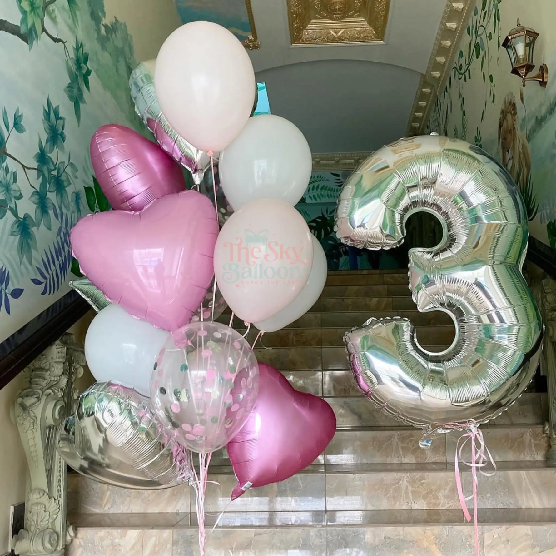 Bunch of balloons including heart-shaped and number '3' foil balloons in a decorative interior setting.