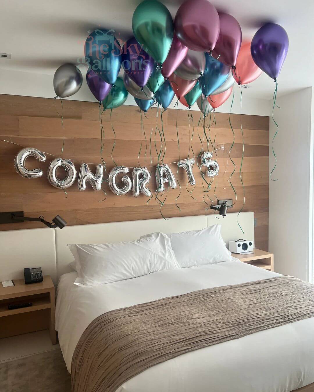 Bedroom with 'CONGRATS' balloons and wooden headboard