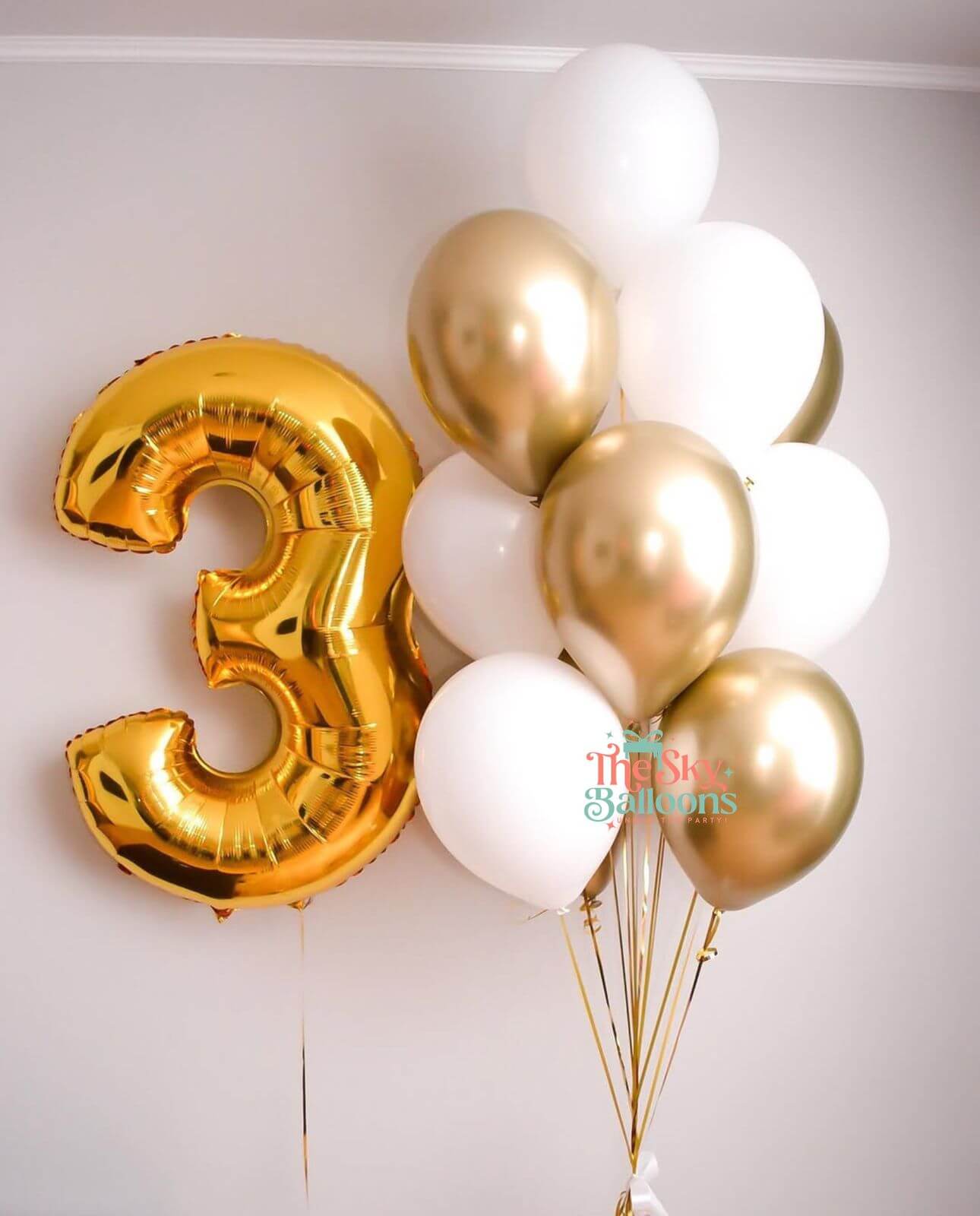 Gold number 3 balloon and white and gold balloons on a light background
