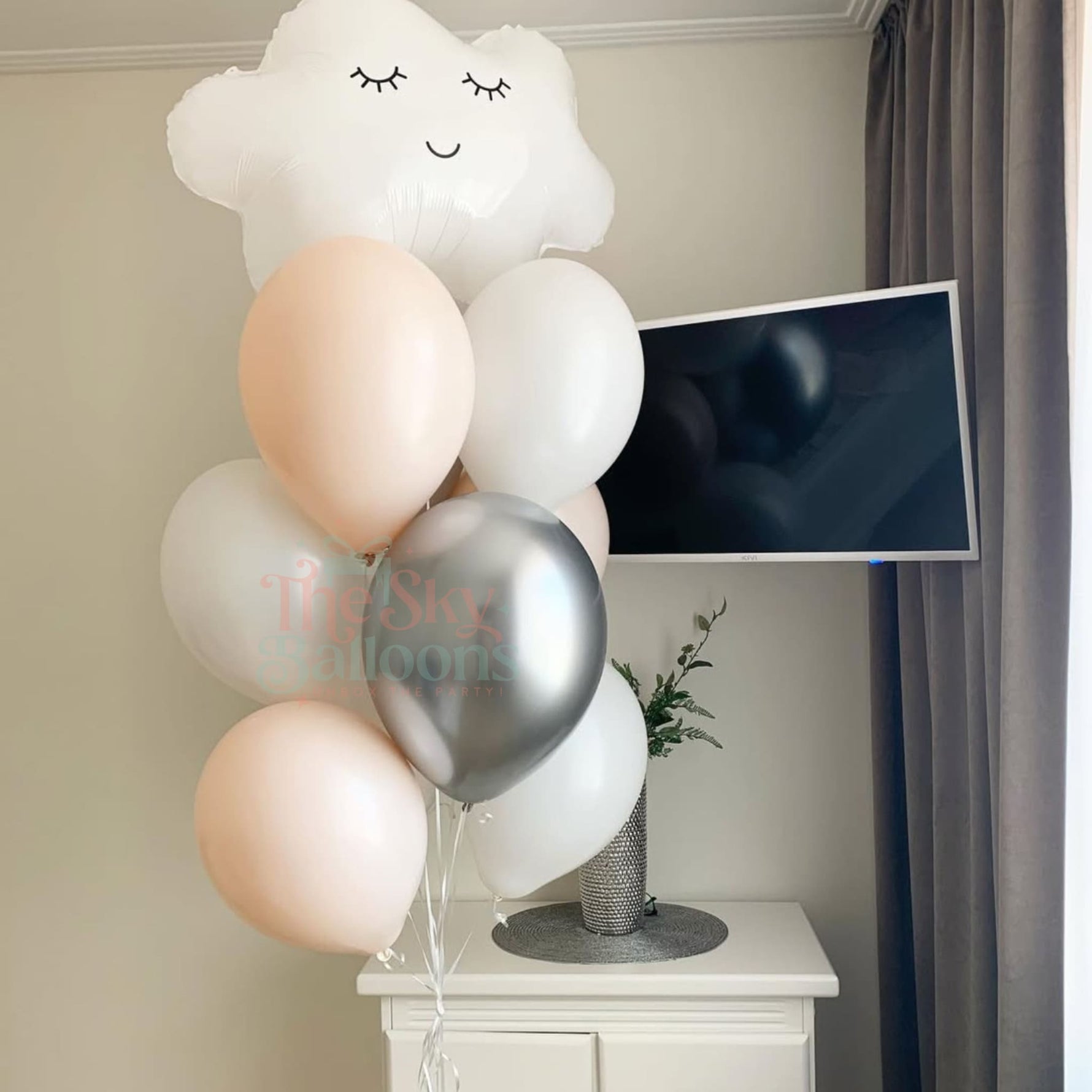 Decorative balloon arrangement with a cloud-shaped balloon in front of a television.