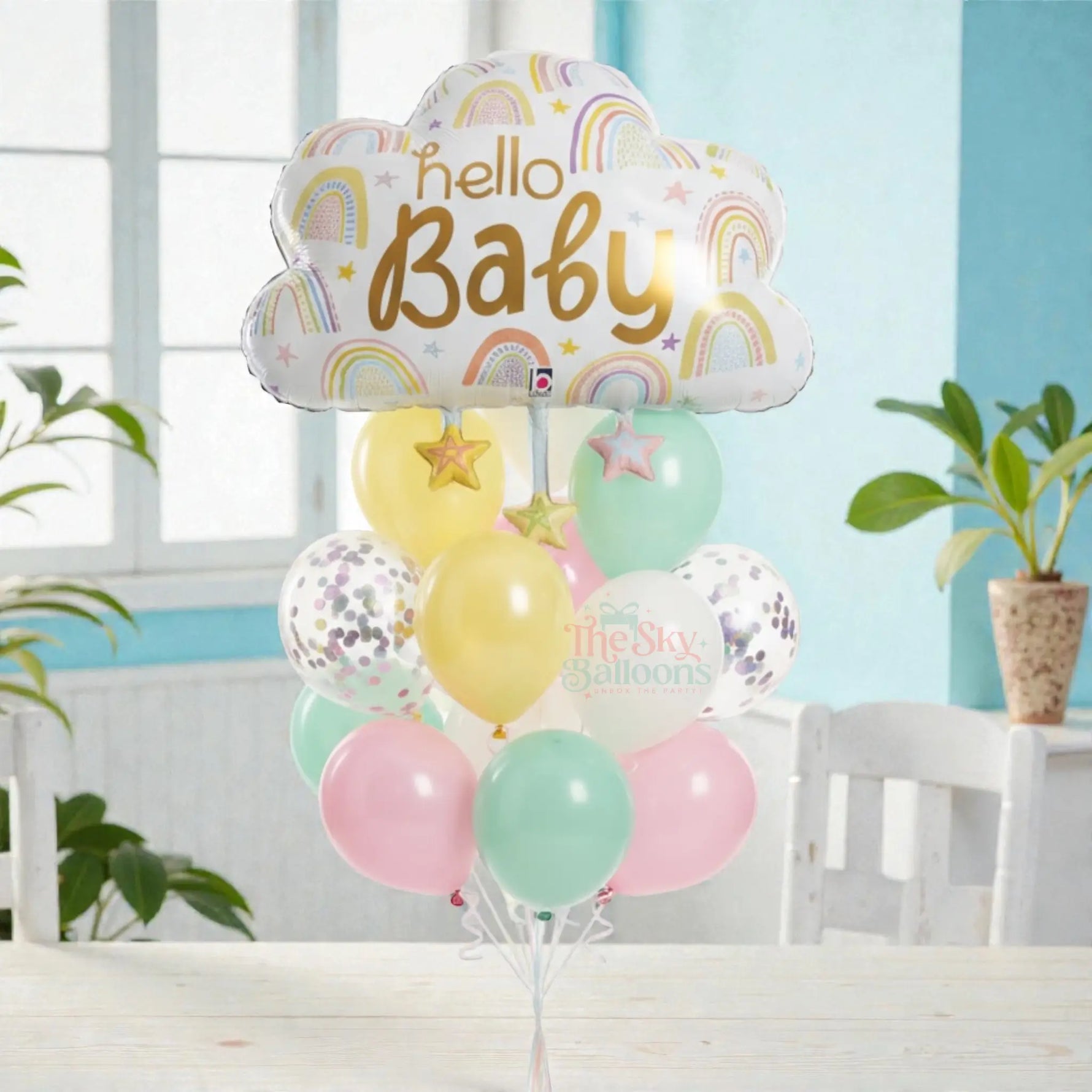 Colorful balloon bouquet with 'hello Baby' cloud balloon on a table.