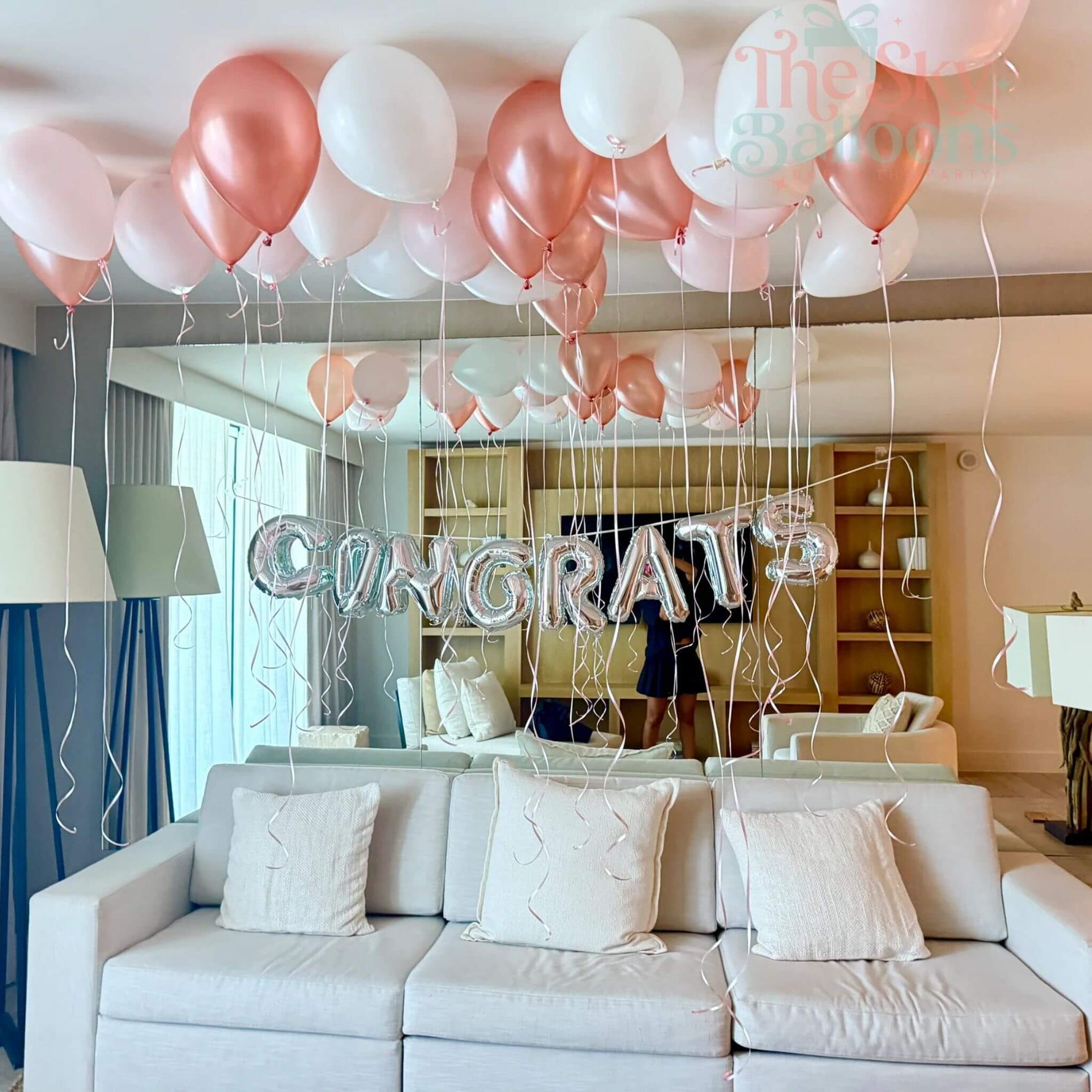 Decorated living room with balloons and 'CONGRATULATIONS' letter balloons.