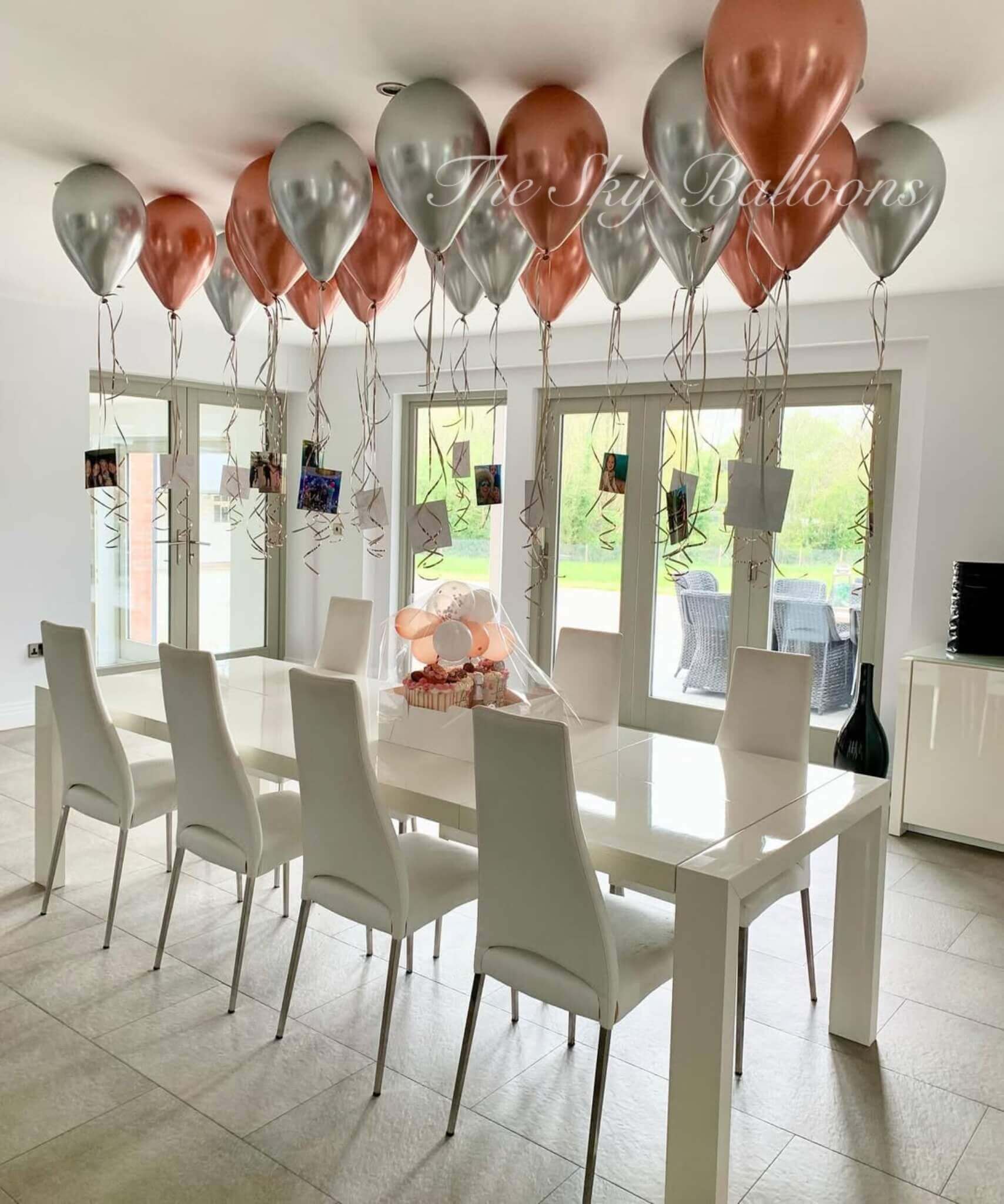 Dining room with a white table and chairs, balloons, and a view of the outdoors.