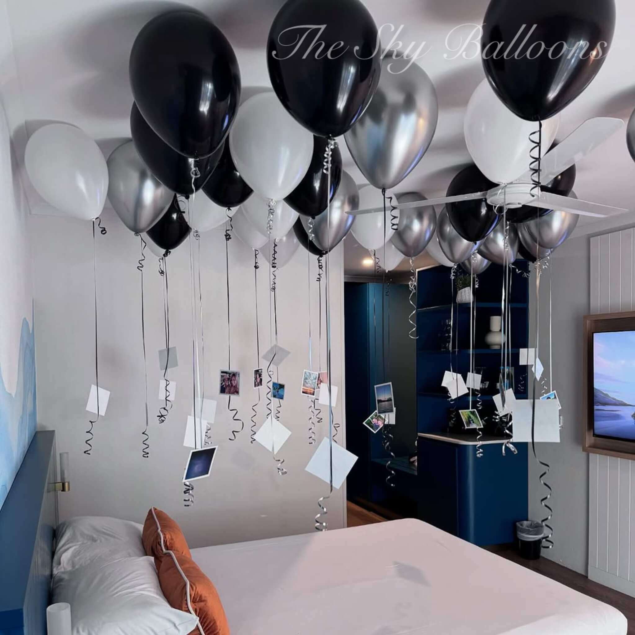 Decorative balloons and streamers in a room with a bed and television.