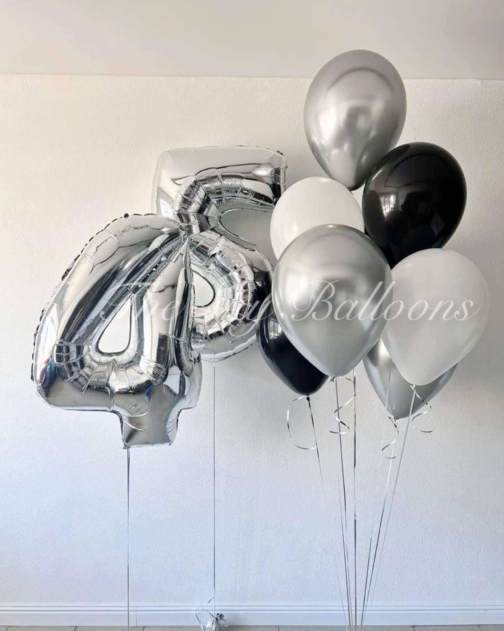 Bunch of silver, black, and white balloons against a white background