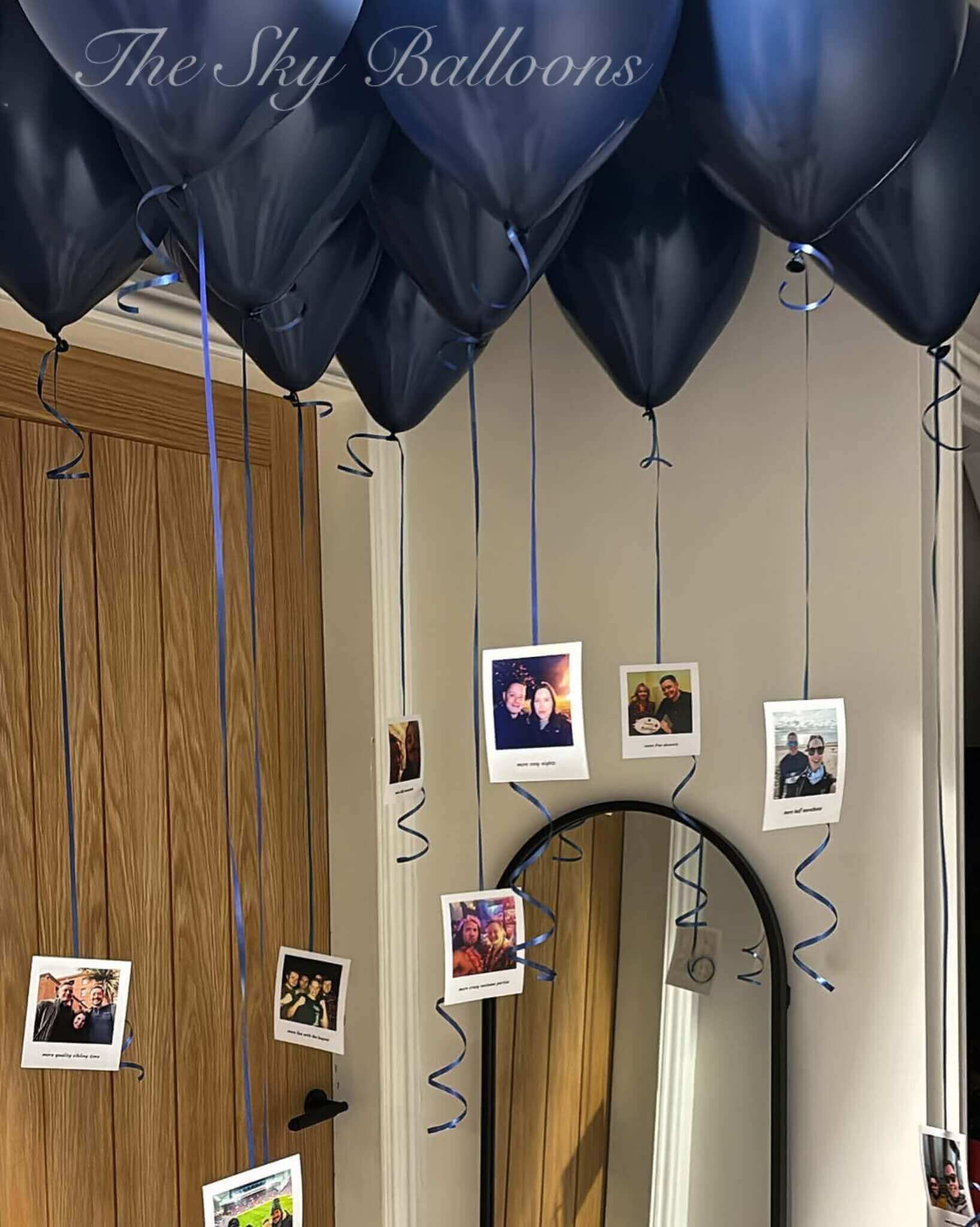 Nvay Blue balloons with blue strings attached to a mirror with photos hanging from them, labeled 'The Sky Balloons'.
