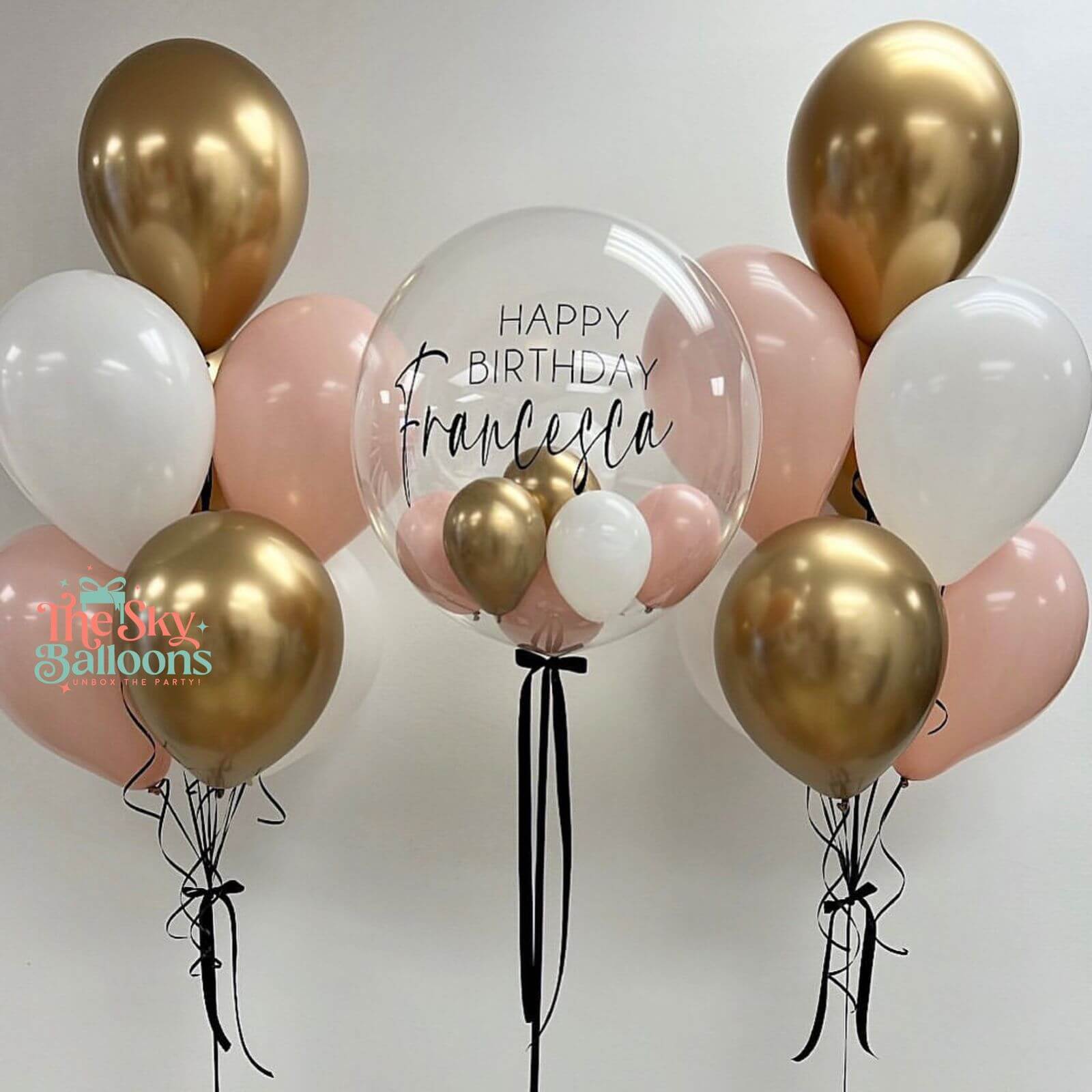 Balloon arrangement with gold, pink, and white balloons, featuring a clear balloon with 'Happy Birthday Francesca' text.