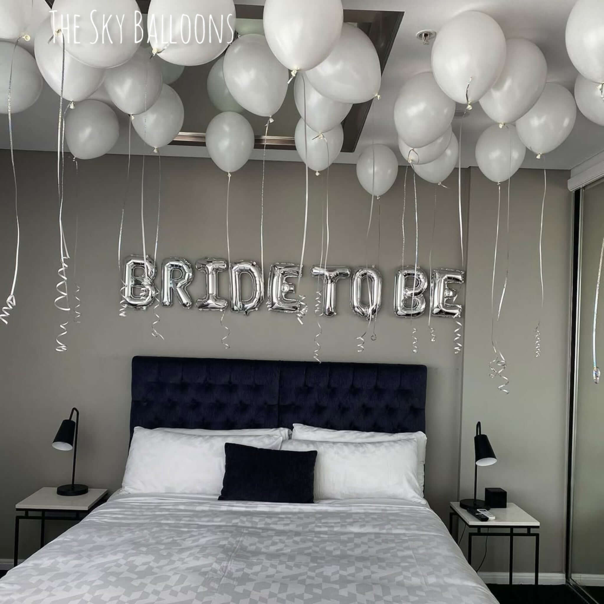 Decorated bedroom with 'BRIDE TO BE' balloons above a bed.