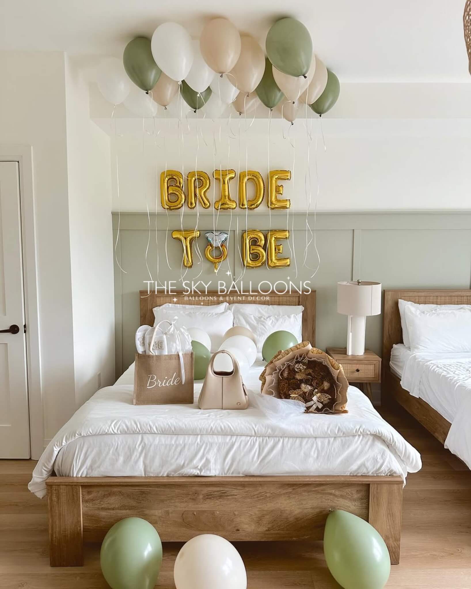 Decorated bedroom with 'Bride to Be' balloons and a bed with white bedding.