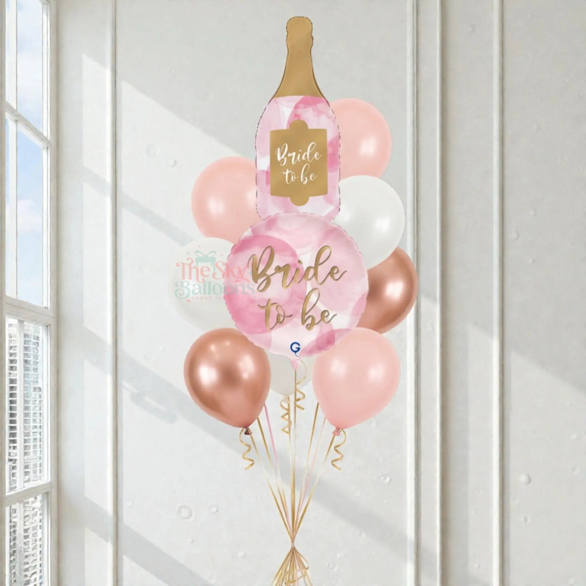 Decorative balloon bouquet with 'Bride to be' and champagne bottle design in a bright room.