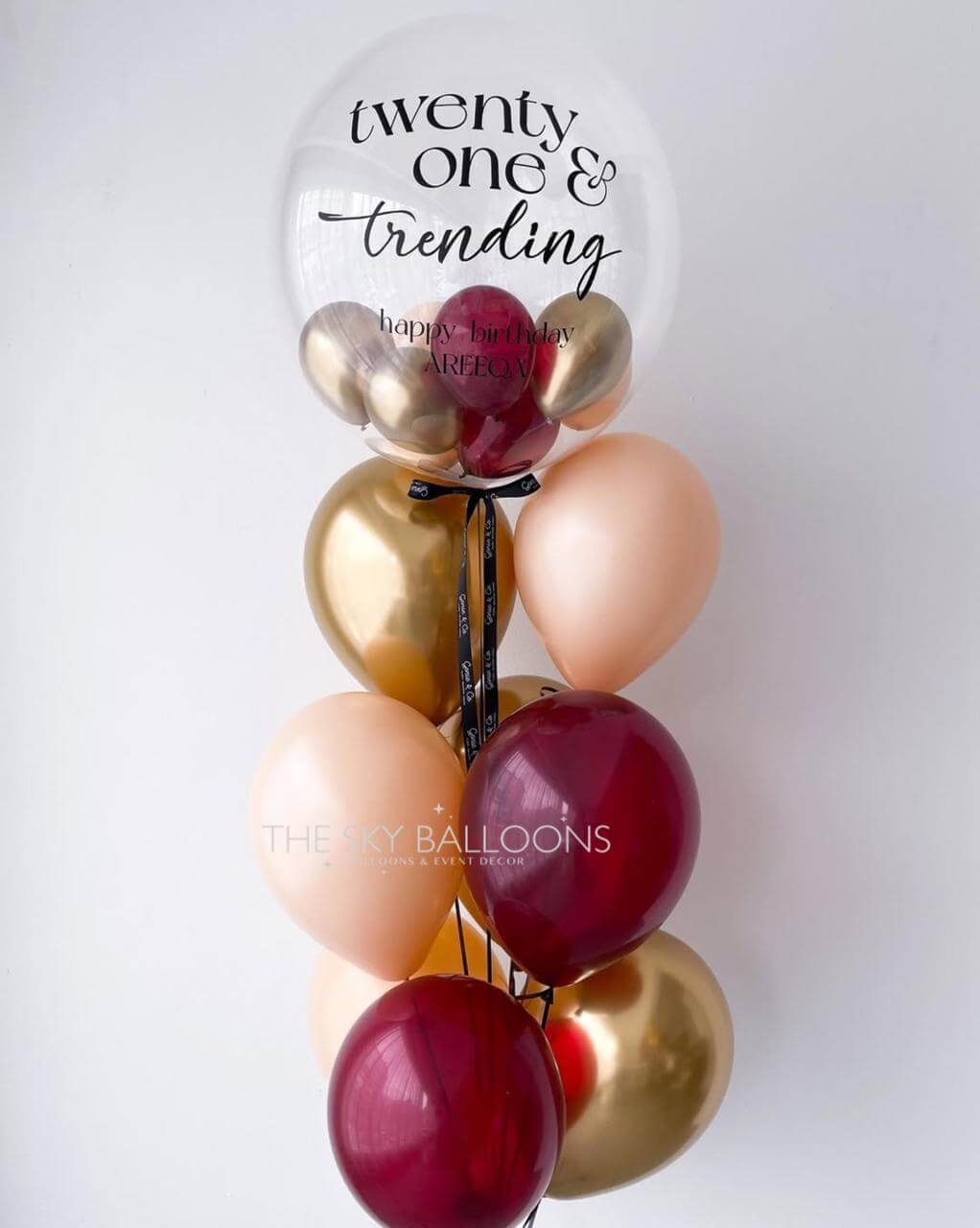 Decorative balloon bouquet with 'twenty one & trending' text on a white background