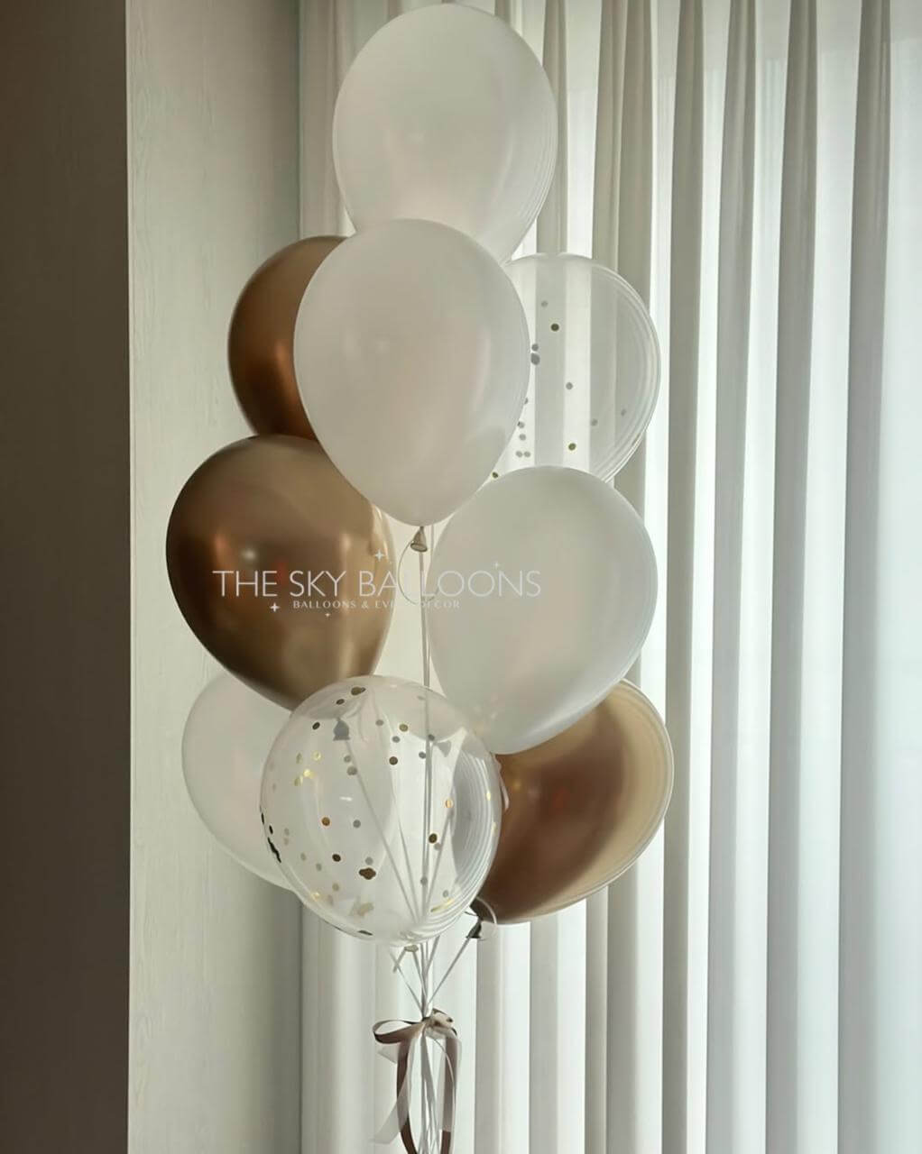 Decorative balloons in gold, white, and clear with 'The Sky Balloons' branding against a window.