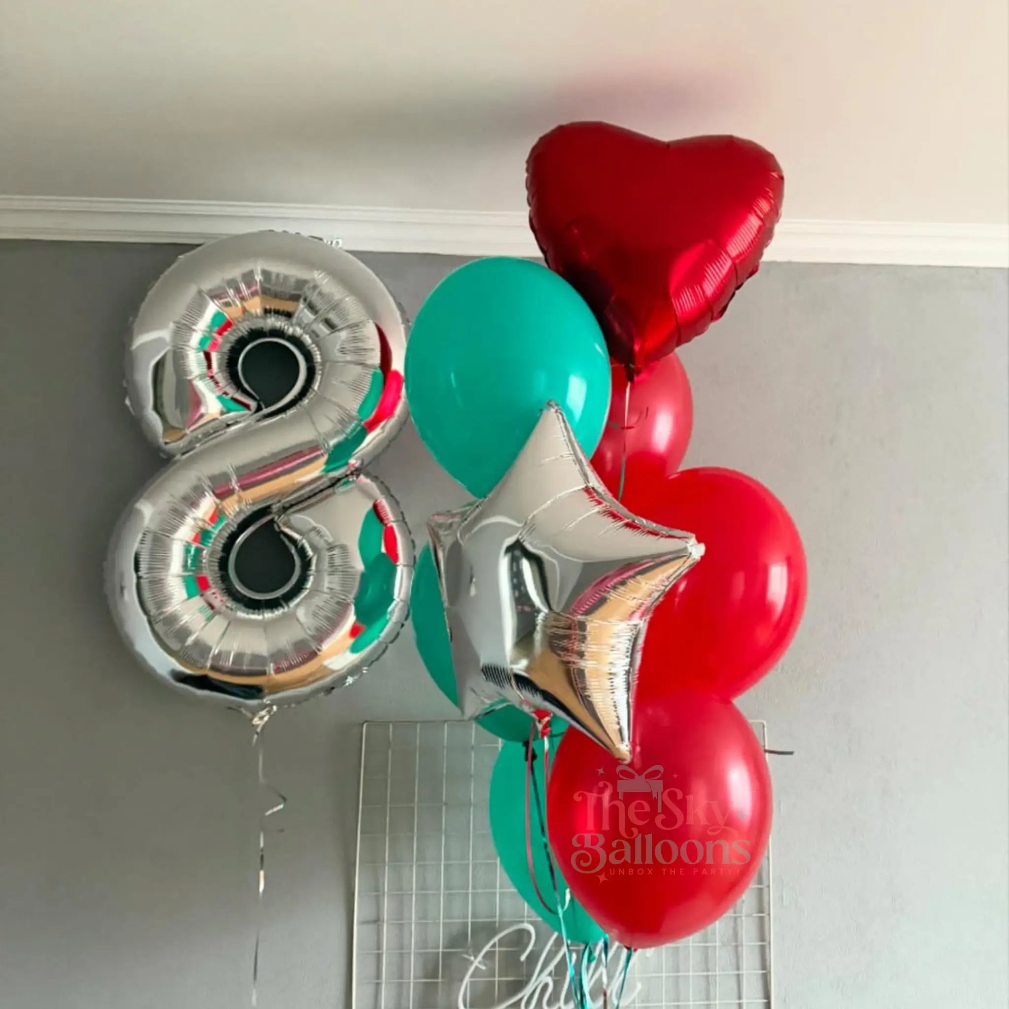 Decorative balloons including a silver number 8, red heart, and green star on a white background.